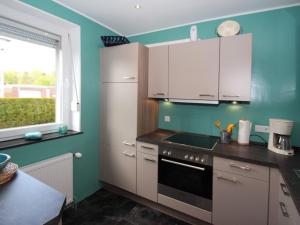 Una cocina con gabinetes blancos y una ventana. en Bungalow in Berumbur nahe Norddeich Strand, en Berumbur