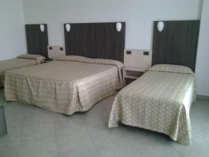 Hotel Lux في مودينا: غرفة في فندق بثلاث اسرة في غرفة