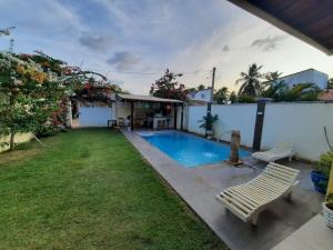 a backyard with a swimming pool and two benches at casa praia de guajiru in Trairi