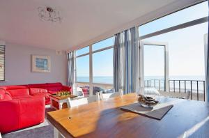 a living room with a table and a red couch at Marine Court - Bognor Regis in Bognor Regis
