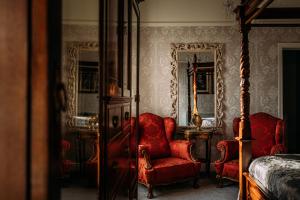 a bedroom with red chairs and a bed and mirrors at The Queens Hotel in Lytham St Annes