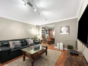 un soggiorno con divano nero e tavolo di Maya residence a Bourne End