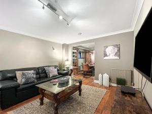 a living room with a black couch and a table at Maya residence in Bourne End