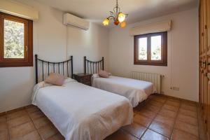two beds in a room with two windows at Villa Es Socorrat in Na Xamena