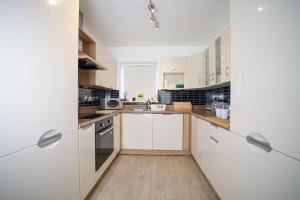 uma cozinha com armários brancos e electrodomésticos de aço inoxidável em 3 bedroom house in Birmingham City centre - Sleeps 6 (Netflix included) em Birmingham