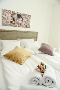 Una cama blanca con toallas y flores. en Suncokret Apartmani Loznica en Loznica