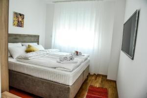 a bedroom with a bed with white sheets and a window at Suncokret Apartmani Loznica in Loznica