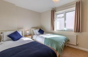 two beds in a small room with a window at Cottage On The Quay in Wroxham