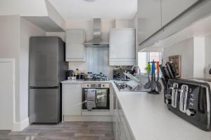 una cocina con electrodomésticos de acero inoxidable y armarios blancos en Spacious 3 Bed House, Netflix, Garden, Parking en Southampton