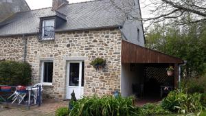 ein Steinhaus mit einer Veranda und einem Fenster in der Unterkunft Gite la Ville Brunet in Saint-Briac-sur-Mer