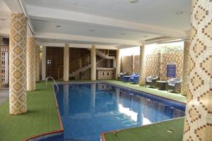 a swimming pool in a hotel with chairs and tables at Grand Star Hotel in North Legon