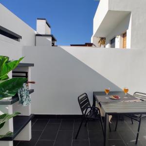 un patio con mesa, sillas y una pared blanca en Apartamentos LOS GATA GATA, en Las Negras