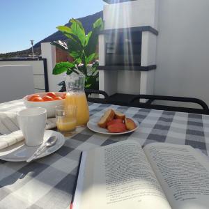 an open book sitting on a table with a table cloth with a plate of fruit at Apartamentos LOS GATA GATA in Las Negras