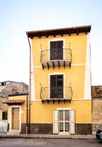 Edificio amarillo con 2 balcones y 2 ventanas en Casa Vacanze A' Lanterna en Licata