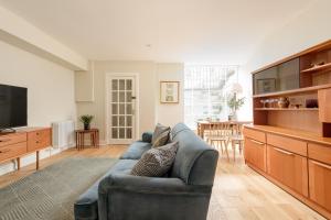 a living room with a blue couch and a television at The Broughton St. Apartment (1BR) - New Town in Edinburgh