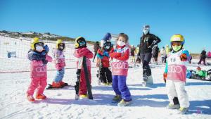 un grupo de niños parados en la nieve con tablas de snowboard en Casa Rural & SPA Mirador de la Covatilla en Guijo de Ávila