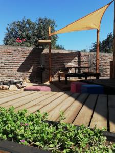 una terrazza in legno con tavolo da picnic e baldacchino. di RdA Cabaña a Pichilemu