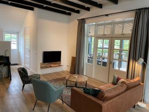 a living room with a couch and a tv at Beautiful apartment with covered terrace, in a holiday park near Rhenen in Elst