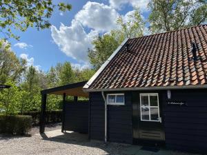 a small blue house with a brown roof at Beautiful apartment with covered terrace, in a holiday park near Rhenen in Elst