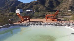 two wooden chairs sitting next to a pool of water at ECOCABAÑAS CERRO ARKO in Mendoza