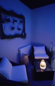 une chambre bleue avec un canapé et une chaise dans l'établissement Gite Romantique avec Espace Balnéo et Ciel Etoilé "La Maison du Bonheur Saint Germer de Fly" Nuit Romantique Oise, Picardie, Normandie, à Saint-Germer-de-Fly