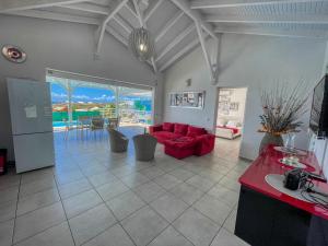 a living room with a red couch and a table at Villa piscine vue exceptionnelle mer et plage in Saint-François