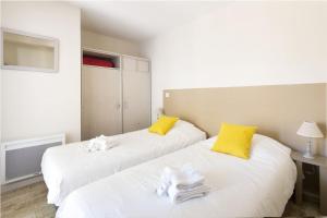 two beds in a room with yellow and white pillows at Belle location Spa et grande terrasse privés in La Couarde-sur-Mer