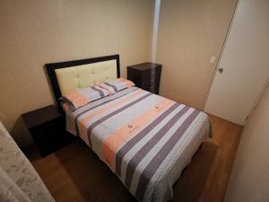 Dormitorio pequeño con cama con manta a rayas en Departamento amoblado en condominio - 5to piso, en Tacna