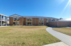 a large building with a grass yard in front of it at Days Inn by Wyndham Dothan in Dothan