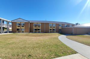 a large building with a grass yard in front of it at Executive Inn & Suites in Dothan