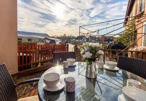 a glass table with a vase of flowers on a balcony at Cottage On The Quay in Wroxham