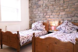 two beds in a bedroom with a brick wall at Stable Cottage in Pateley Bridge