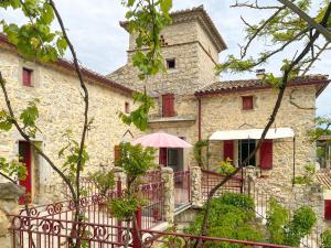 - un grand bâtiment en pierre avec un parasol rose dans l'établissement Mas Bourdaric - Location de Gites en Ardeche du Sud, à Saint-André-de-Cruzières