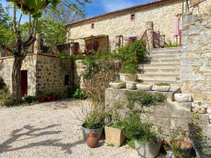 un bâtiment en pierre avec des escaliers et des plantes en pot dans l'établissement Mas Bourdaric - Location de Gites en Ardeche du Sud, à Saint-André-de-Cruzières