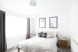 ein weißes Schlafzimmer mit einem Bett und zwei Bildern an der Wand in der Unterkunft Willow Cottage in Pateley Bridge + 19 Fotos