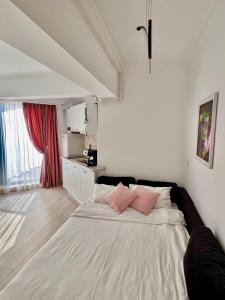 una camera da letto con un grande letto bianco con cuscini rosa di Kitty Studio Sunset Lake a Mamaia