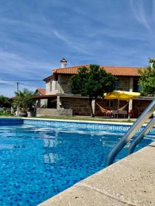 ein blauer Pool mit einem Haus im Hintergrund in der Unterkunft Casa da Clarinha in Penalva do Castelo