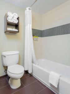 a white toilet sitting next to a bath tub in a bathroom at Sonesta ES Suites Anaheim Resort Area in Anaheim