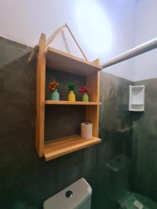 a bathroom with a wooden shelf above a toilet at Pousada Hospedaria Nativus Caraiva in Caraíva