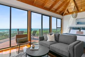 ein Schlafzimmer mit einem Sofa und einem Bett sowie einem Balkon in der Unterkunft Point of View Villas in Apollo Bay