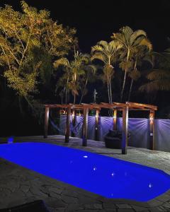Sunset Maresias- Casas e Chalés C3 في ماريسياز: مسبح ازرق في الليل مع النخيل