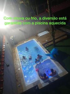 a swimming pool with people in the water at Casa de praia, piscina aquecida, cervejeira e bilhar in Bertioga
