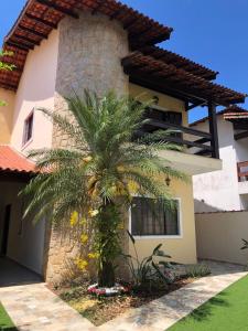 a palm tree in front of a house at Casa de praia, piscina aquecida, cervejeira e bilhar in Bertioga