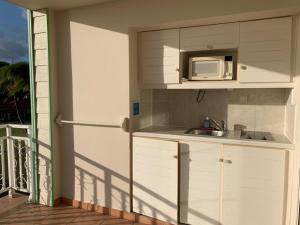 a kitchen with a sink and a microwave on a balcony at Appartement terrasse vue mer dans village Pierre Vacances in Sainte-Luce
