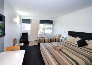 a hotel room with two beds and a desk at Memphis Motor Inn in Parkes