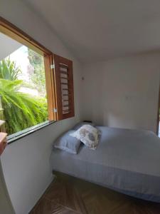 Bett in einem Zimmer mit einem großen Fenster in der Unterkunft CASINHA DA SERRA in Baturité