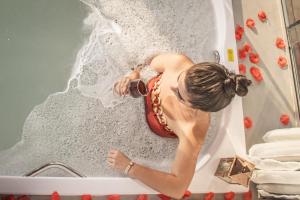 a woman is sitting in a bath tub at Chalé Formoso - Chalé Romântico com Hidromassagem in Serra de São Bento