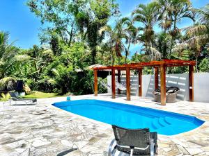 a swimming pool with a pergola and a table at Sunset Maresias- Casas e Chalés C1 in Maresias