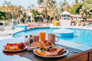 a tray of breakfast food on a table next to a pool at Best Western Jaco Beach All Inclusive Resort in Jacó