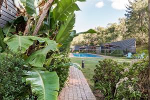 - un jardin avec une passerelle en briques à côté d'une piscine dans l'établissement Yallingup Lodge Spa Retreat, à Yallingup